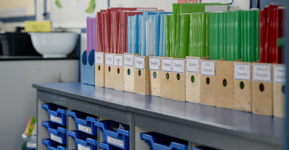 A close-up view of an organized classroom with color-organized wooden desk tidys lined up on the top of a set of classroom drawers. The school is based in Hexham in the North East of England.