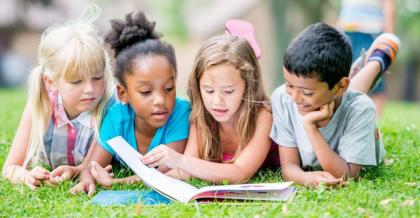 group of kids reading on the grass in summer