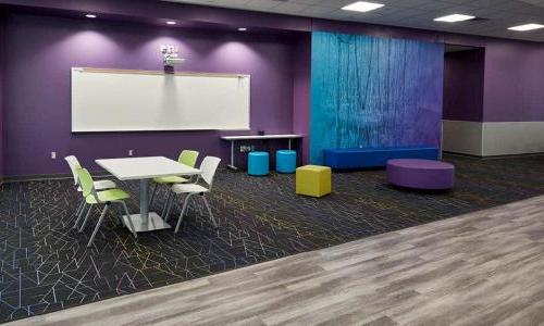 kranz junior high school open common area off the hallway, purple and blue walls, table and chairs, soft and colorful furniture