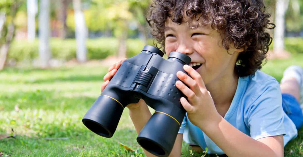 young student learning with binoculars outdoors