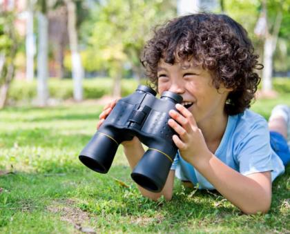 young student learning with binoculars outdoors