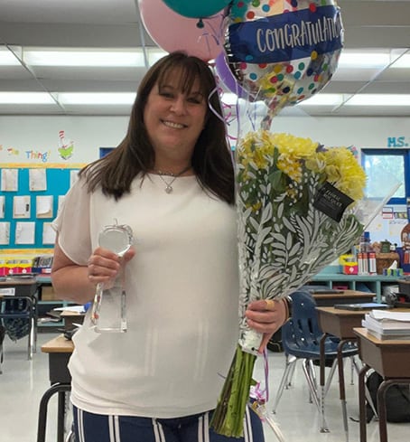 teacher holding congratulatory flowers and balloons