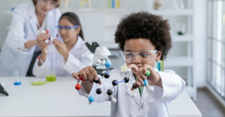 elementary school science student using plastic atom model educational toy