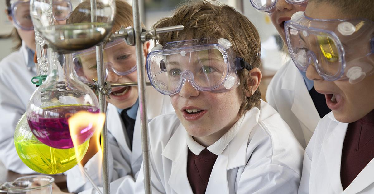 young students watching chemical reaction with bunsen burner