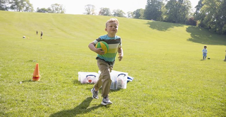 boy playing outside with ball and cones