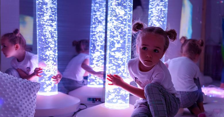 child in sensory room with LED bubble tube for light therapy