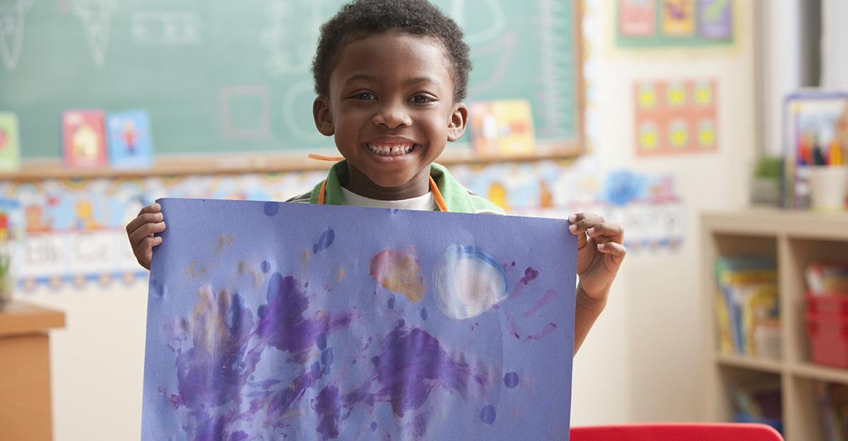 young student holding up art in the classroom