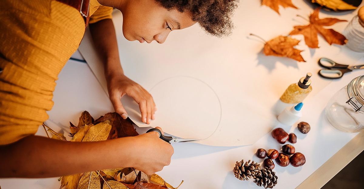 student using leaves and pinecones for autumn art project