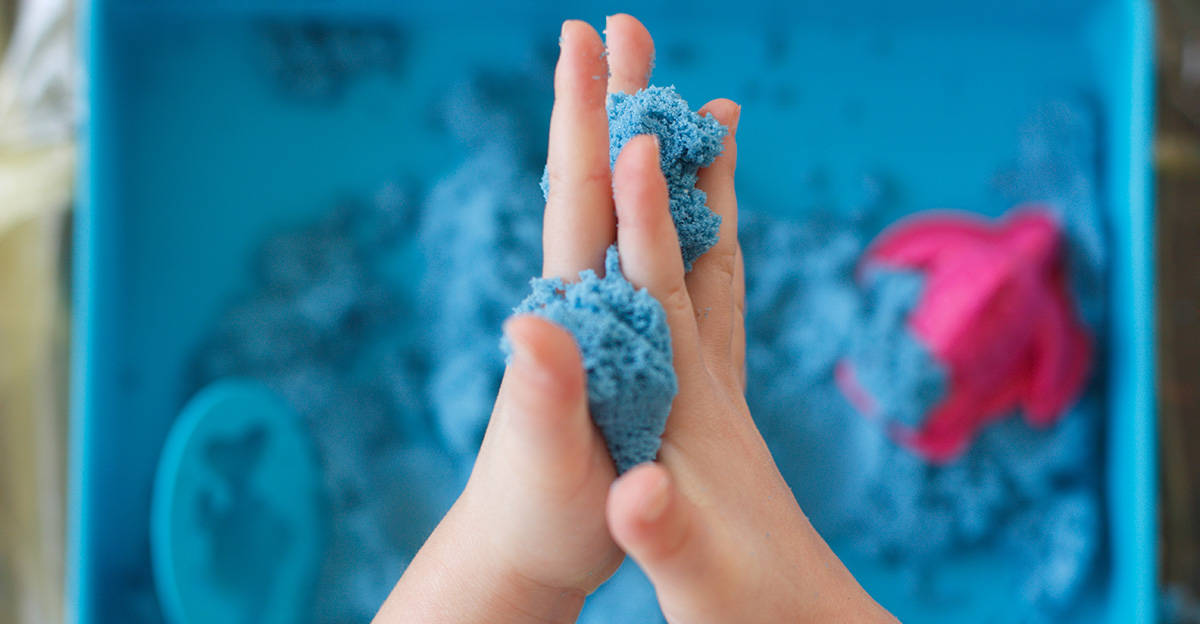 child playing with blue sand for sensory input