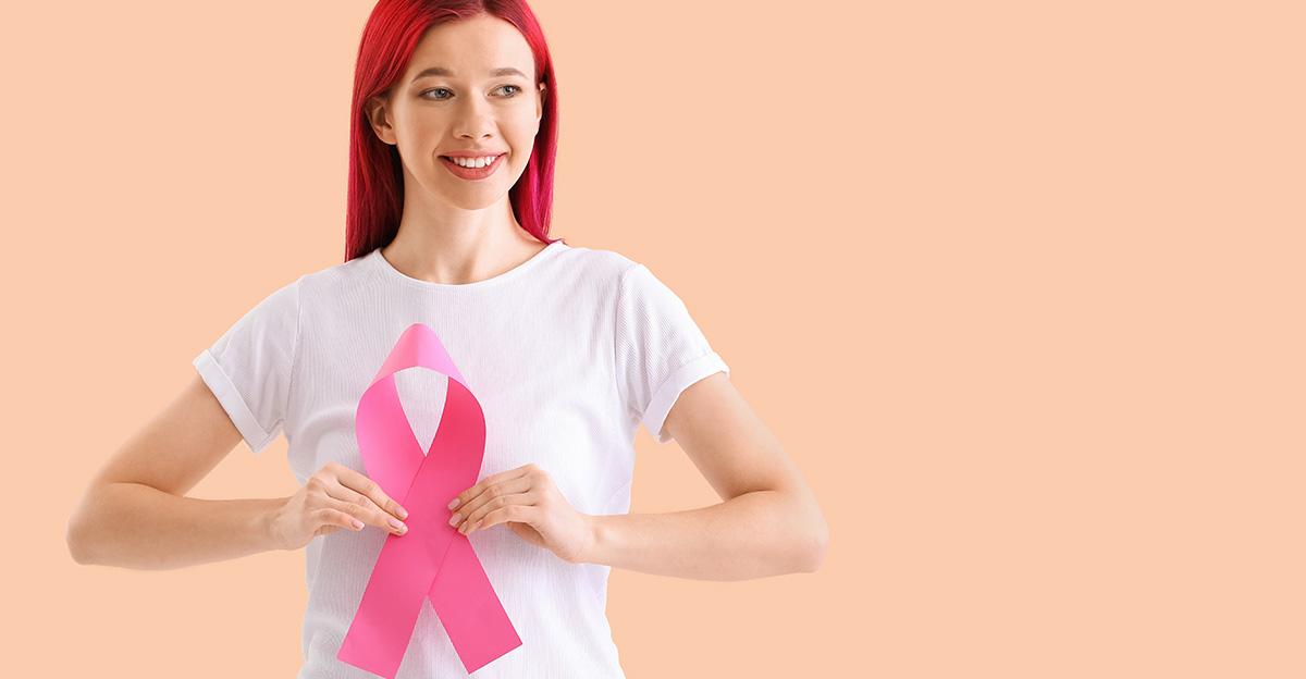 student with pink hair holding breast cancer awareness ribbon