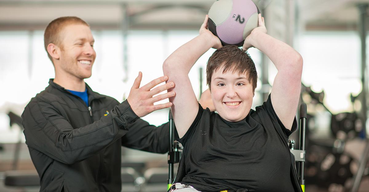 special needs woman in wheelchair doing workout with trainer