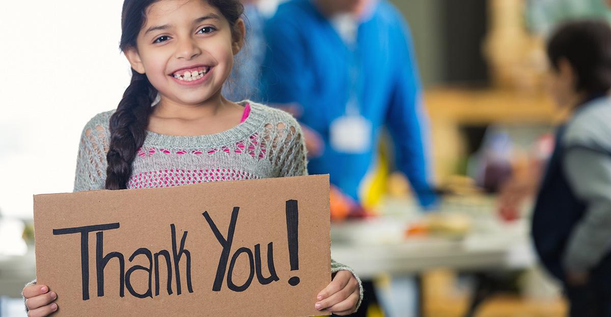 young girl holding thank you sign to show appreciation to volunteers
