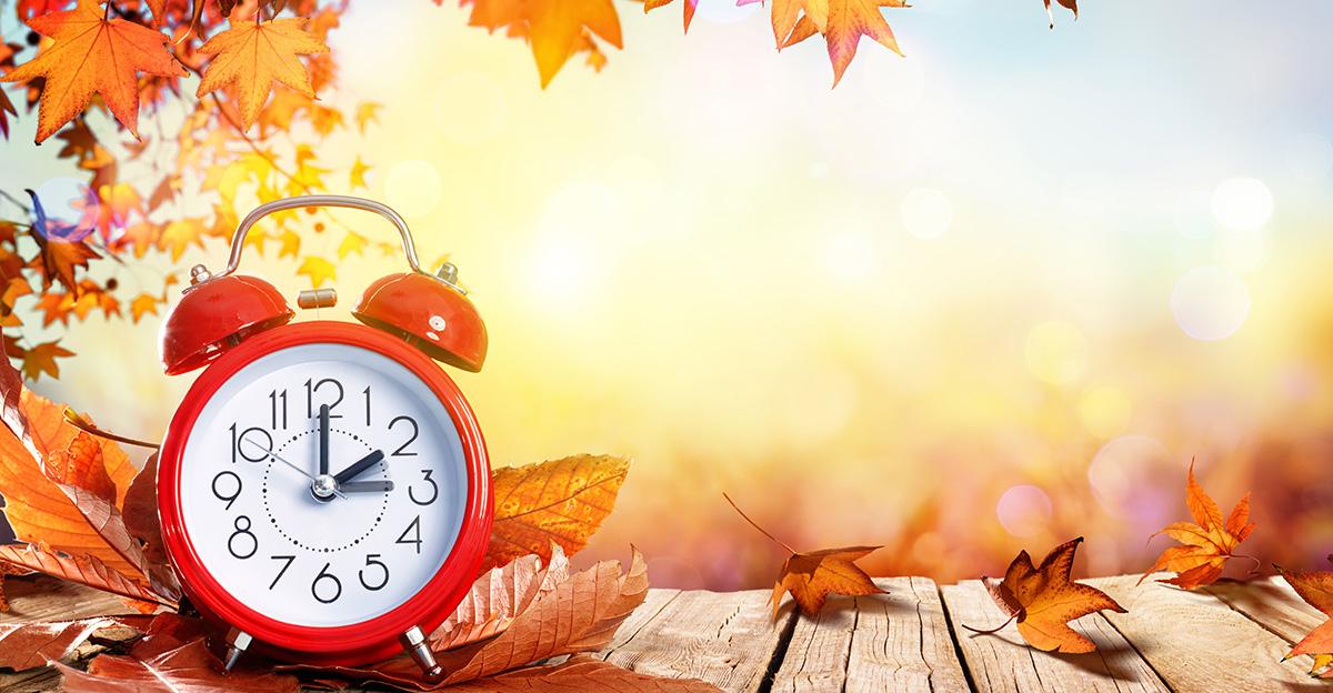 daylight saving time concept with clock and autumn leaves