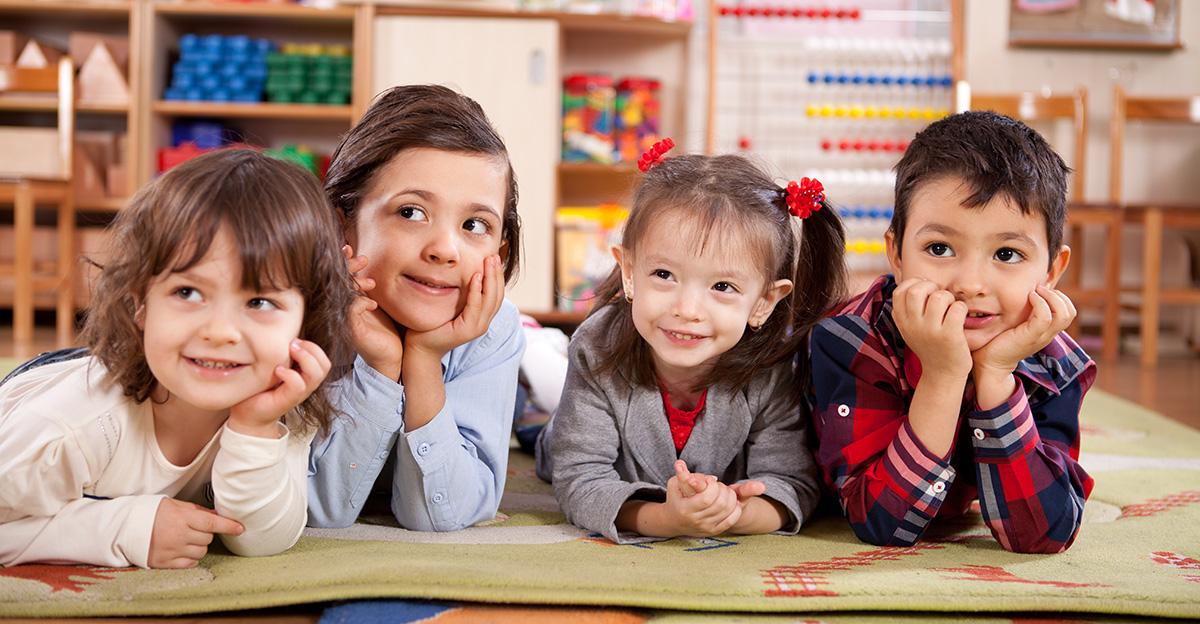 early childhood preschool students lying down on carpet in classroom