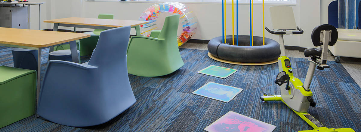 special education and sensory room with soft seating, tables, and exercise bike