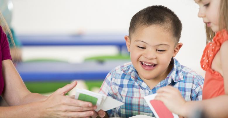 little boy with special needs playing card game in inclusive classroom