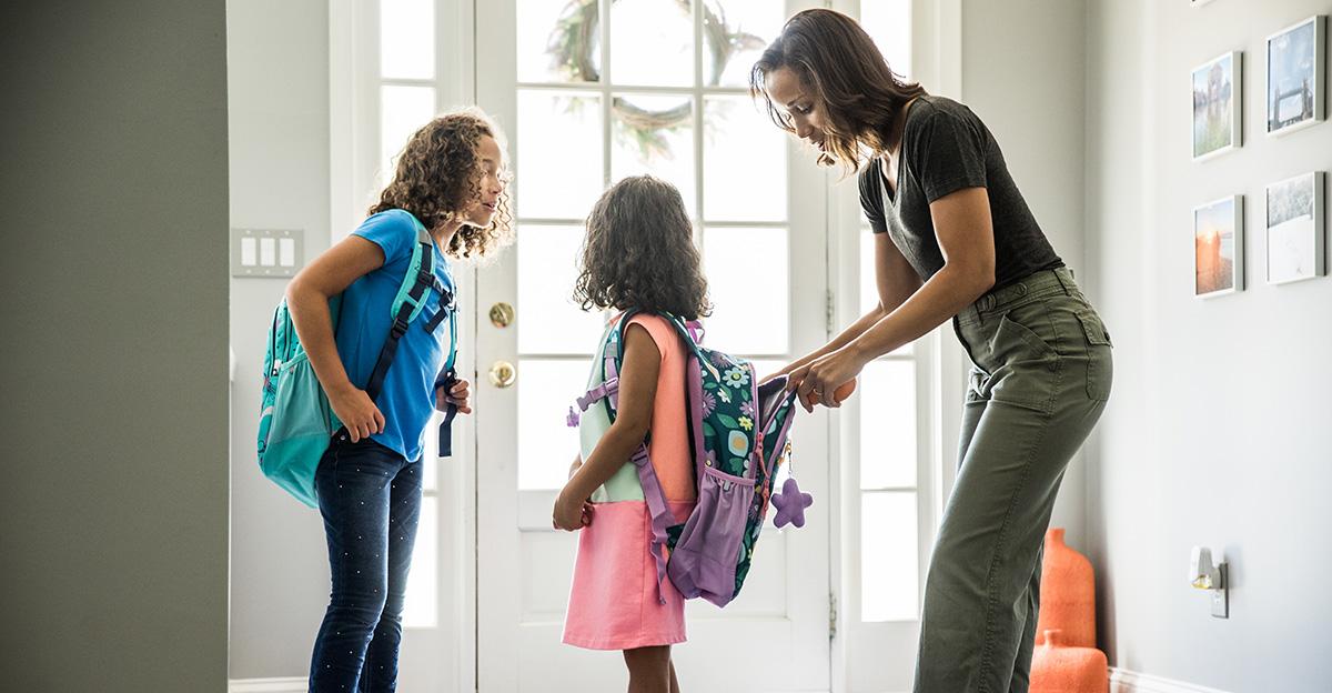 mom packing backpacks for daughters going back to school