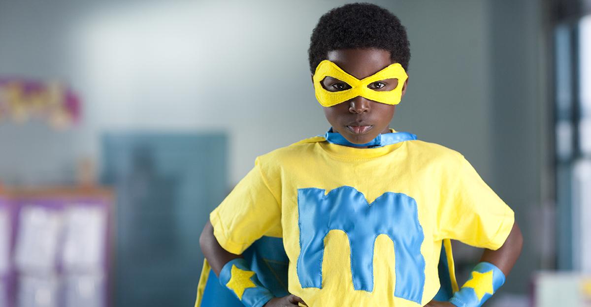 young student wearing superhero costume in the classroom