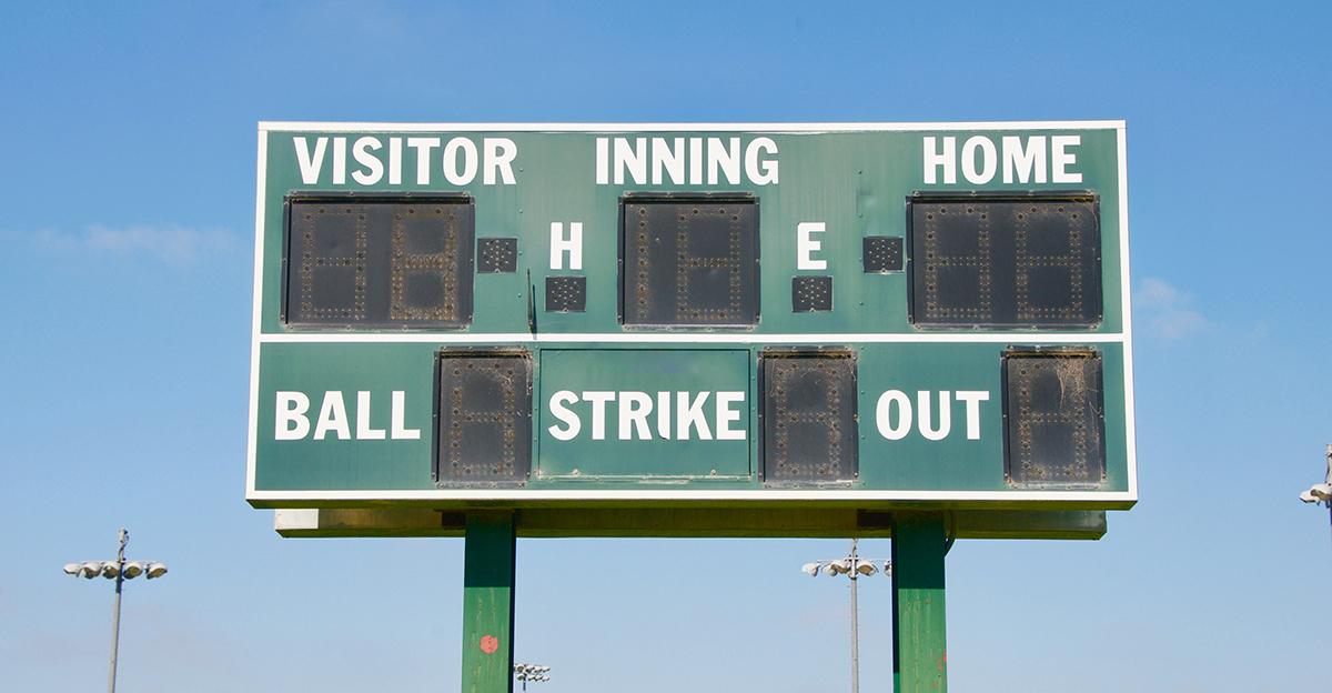 green and white little league baseball scoreboard with blue sky background