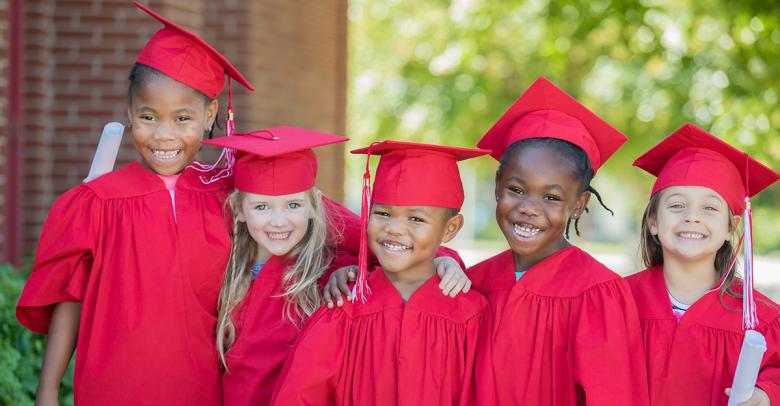 elementary students wearing red gowns and caps for graduation celebration