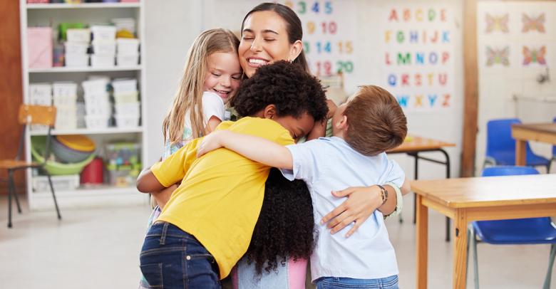 appreciative young students hugging their teacher