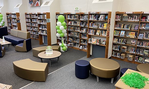 panned view of library media center with bookshelves, tables, and soft seating