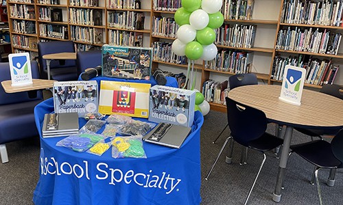 table with school specialty products with balloons and bookshelves in background