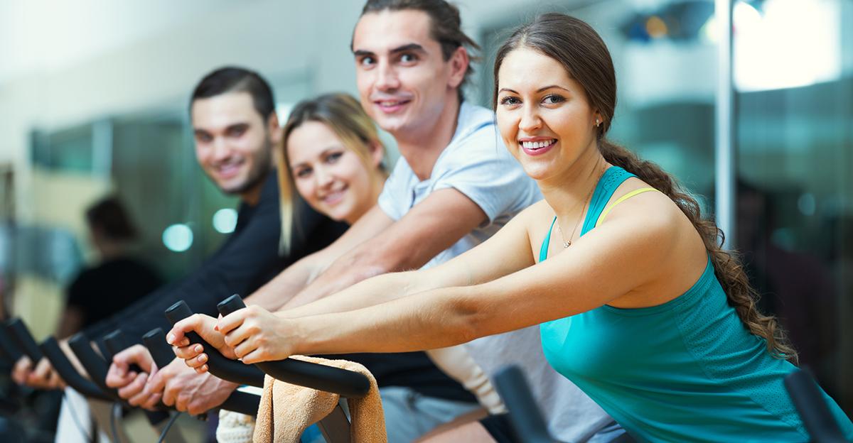 people cycling on stationary bikes at fitness club