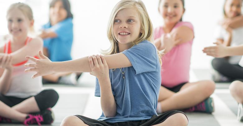 group of children sitting and stretching in physical education class