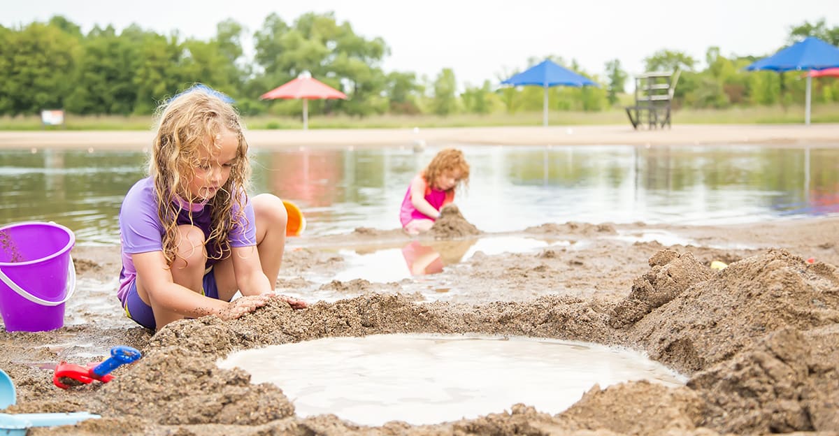 young girls at an outdoor beach doing sand building activities