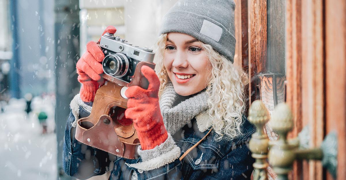 young woman taking photos in the winter with snow falling