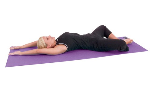 woman laying on her back on yoga mat