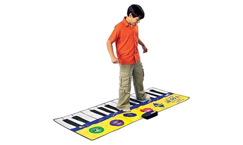 young boy playing music on a giant piano mat