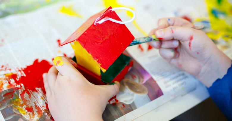 child's hands building and painting a bird house