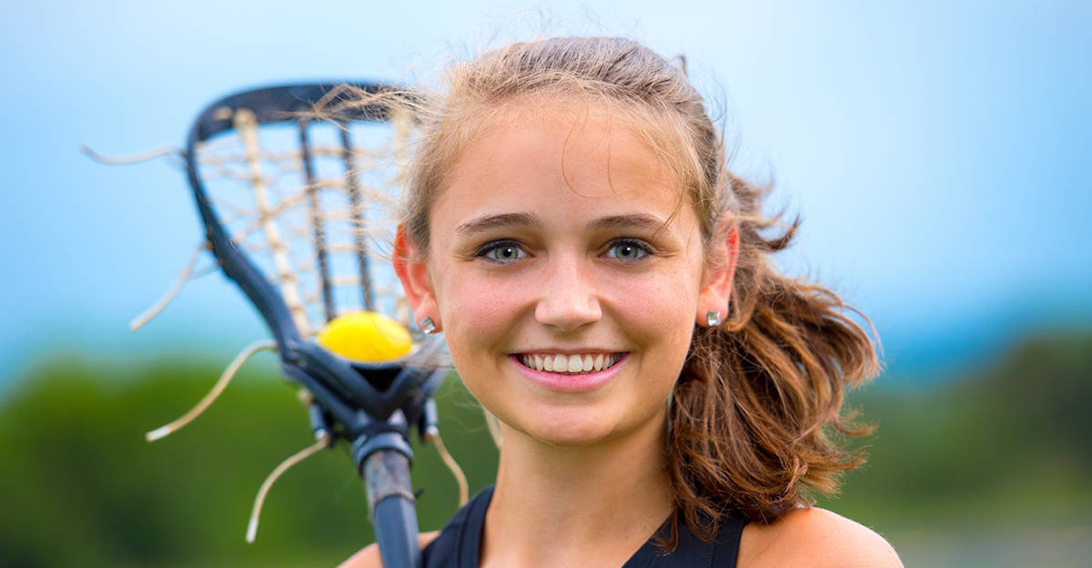 young female lacrosse player holding lacrosse stick