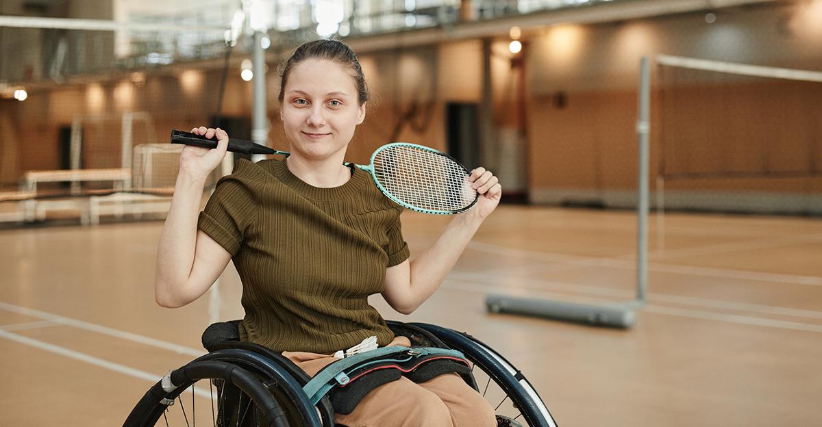 active woman with a disability sitting in wheelchair and holding a badminton racquet
