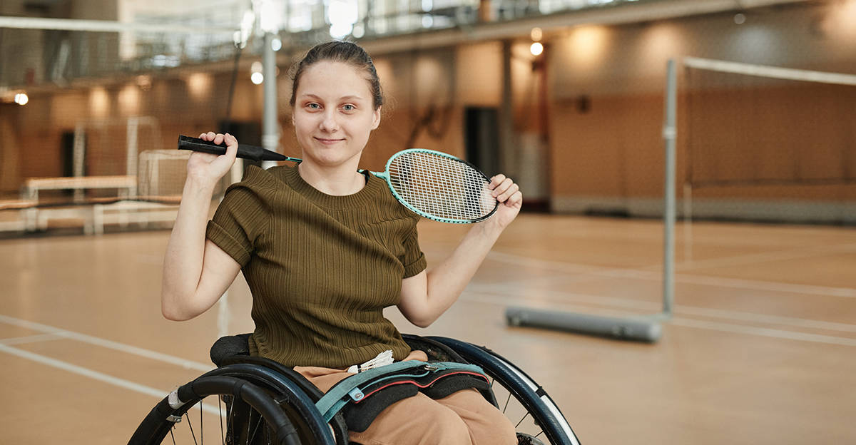 active student with a disability sitting in wheelchair and holding a badminton racquet