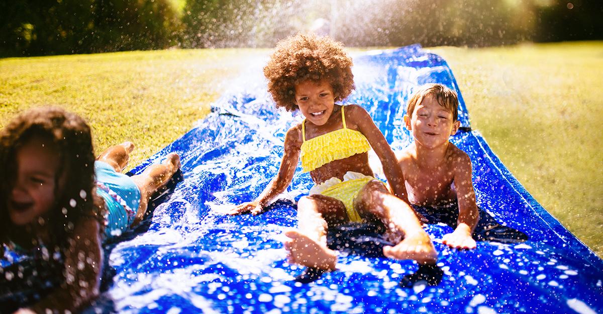 young children player water games and racing down a water slide