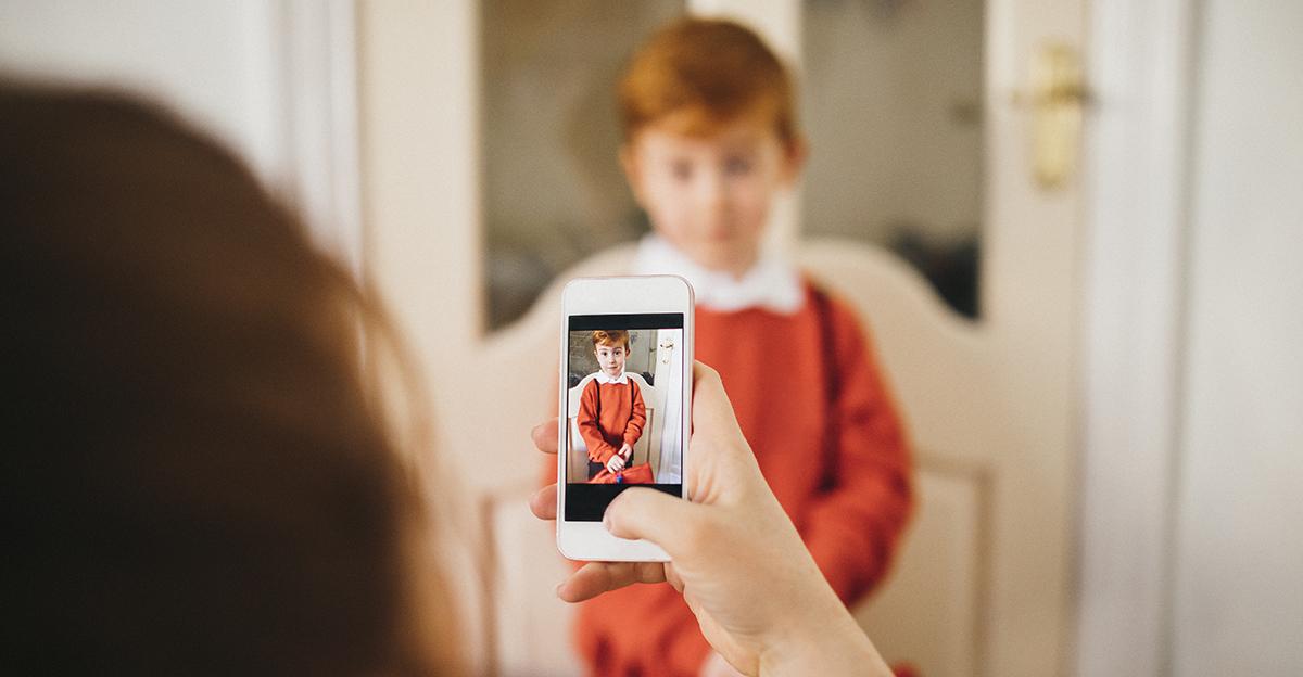 young student ready for back to school and mother taking his picture with a smartphone