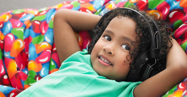 little girl with headphones laying on a beanbag in a sensory space
