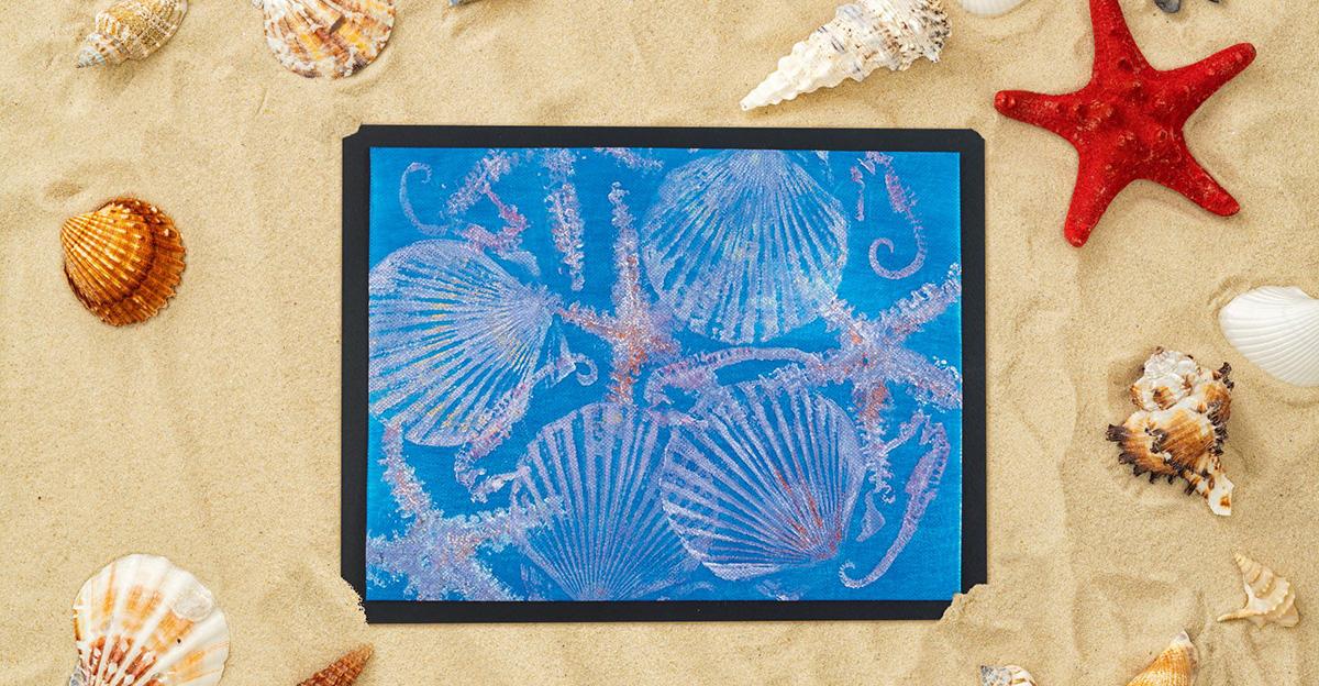 iridescent ocean textile prints art piece on with a sandy beach background covered in seashells