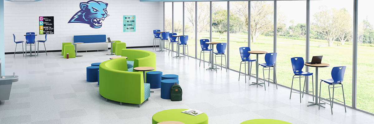 rendering of school common area with green and blue soft seating options and high cafe tables, full length windows along the side and school mascot painting on the back wall