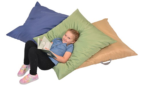 young child reading a book while laying on soft floor pillows