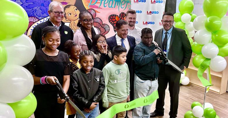 students and teachers cut the ribbon to celebrate the opening of their school's new media center