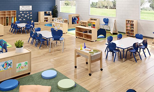 early childhood classroom design with large windows, wooden furniture, sand table, blue chairs
