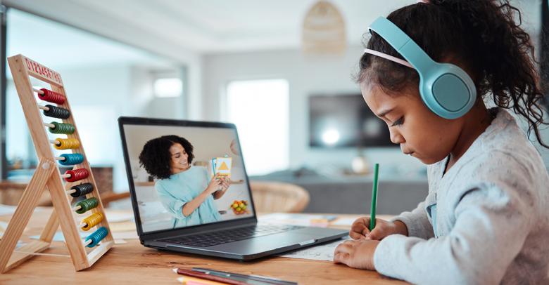 young student at home with headphones, drawing and watching an online lesson from a teacher on a laptop