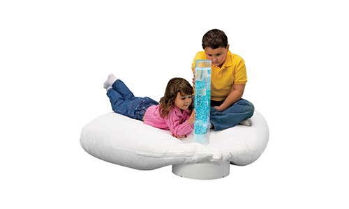 two children sitting on a large pillow looking at a sensory bubble tube
