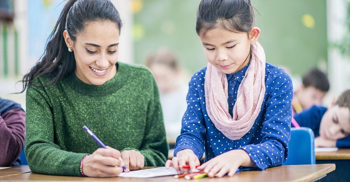 teacher and student smiling and writing with colored pencils