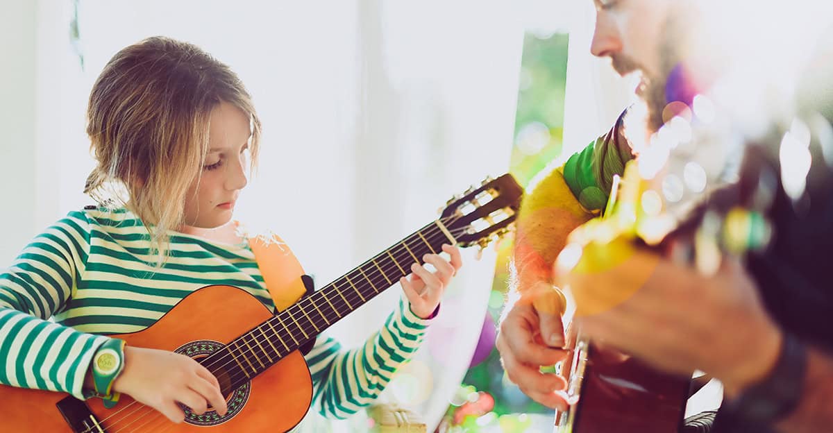 student and adult practice playing music on guitar