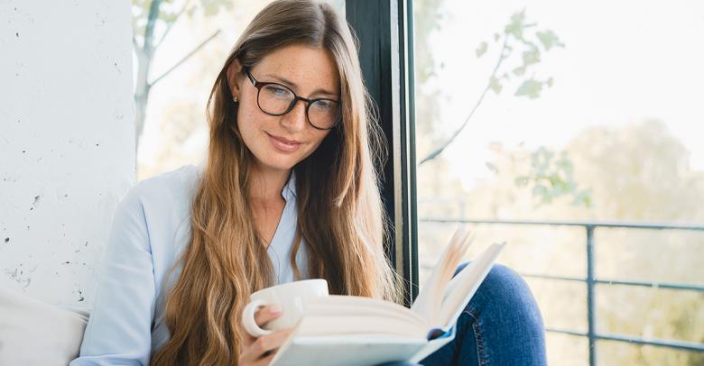 teacher reading a novel and holding a coffee cup, relaxing over summer break